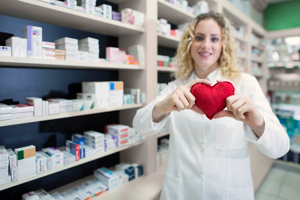 Female pharmacist holding heart and promoting cardiovascular medications and successful treatment